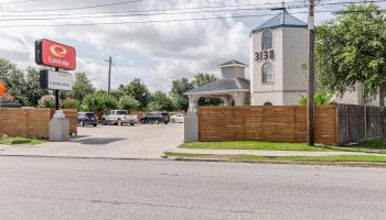 A motel with the number 3138 on the building, a parking lot with cars, and a sign displaying Economy Lodge can be seen in the image.